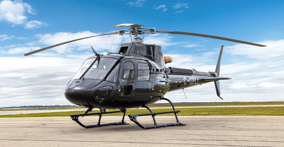 Black Airbus AS350 helicopter parked on the apron